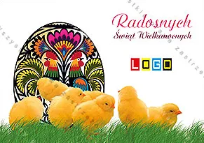 Duża czarna kroszonka w kolorowe kwiaty i tabun żółtych kurcząt na trawie, różowy napis w górnym rogu
